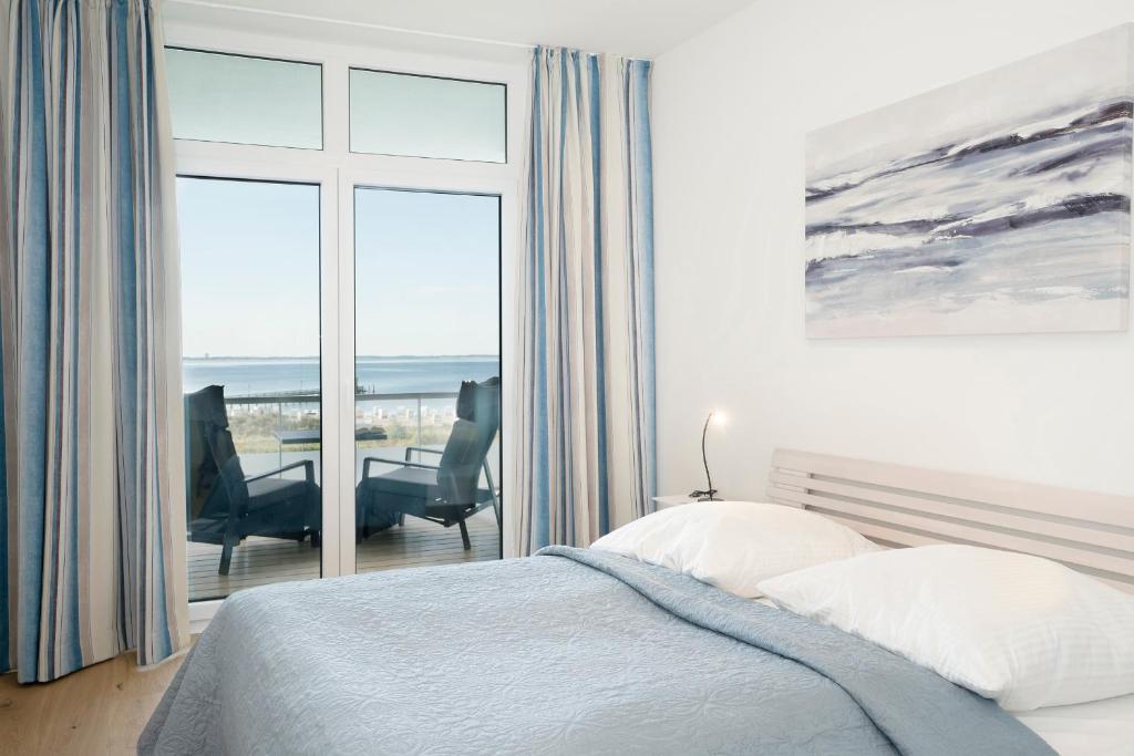 a bedroom with a bed and two chairs and a window at Strandträumer in Pelzerhaken