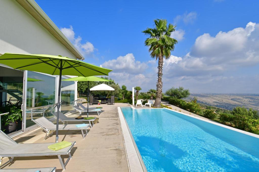 a swimming pool with chairs and a palm tree at Villa Nausica pool view on the sea wifi free perfect for big group in Ragusa