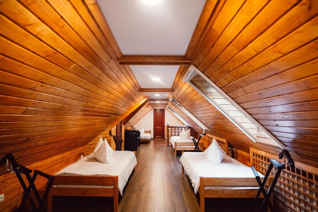 two beds in a room with wooden walls at Casa Cheile Dâmbovicioarei - Cabana 2 in Dîmbovicioara