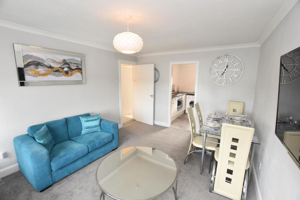 uma sala de estar com um sofá azul e uma mesa em Lovely 2 Bedroom Flat in a quiet location em Airdrie