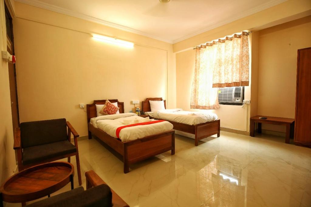 um quarto com 2 camas, uma cadeira e uma janela em DWARKA KUNJ em Vrindavan