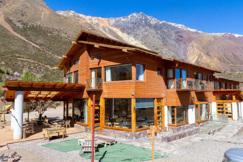 a large wooden house with mountains in the background at Lodge El Morado in Lo Valdés