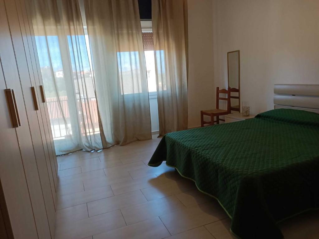 a bedroom with a green bed and sliding glass doors at Casa Antonia in Tempio Pausania