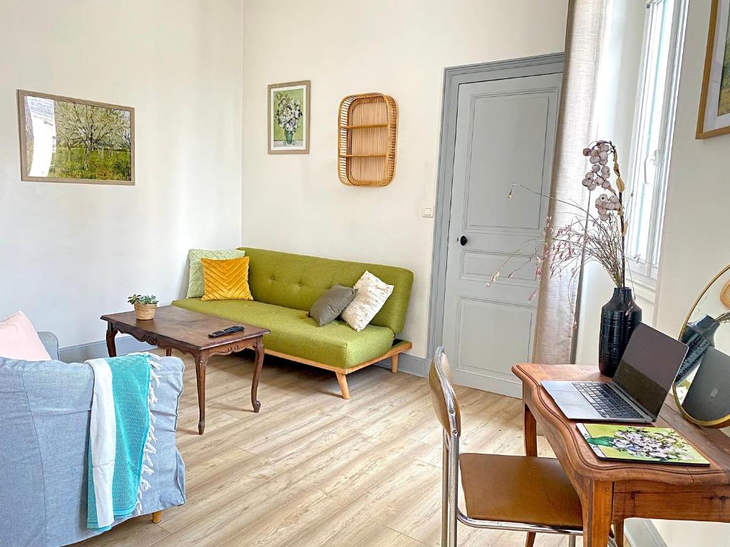 uma sala de estar com um sofá verde e uma mesa em Coeur de Sologne, la Loire et les châteaux. em Dhuizon