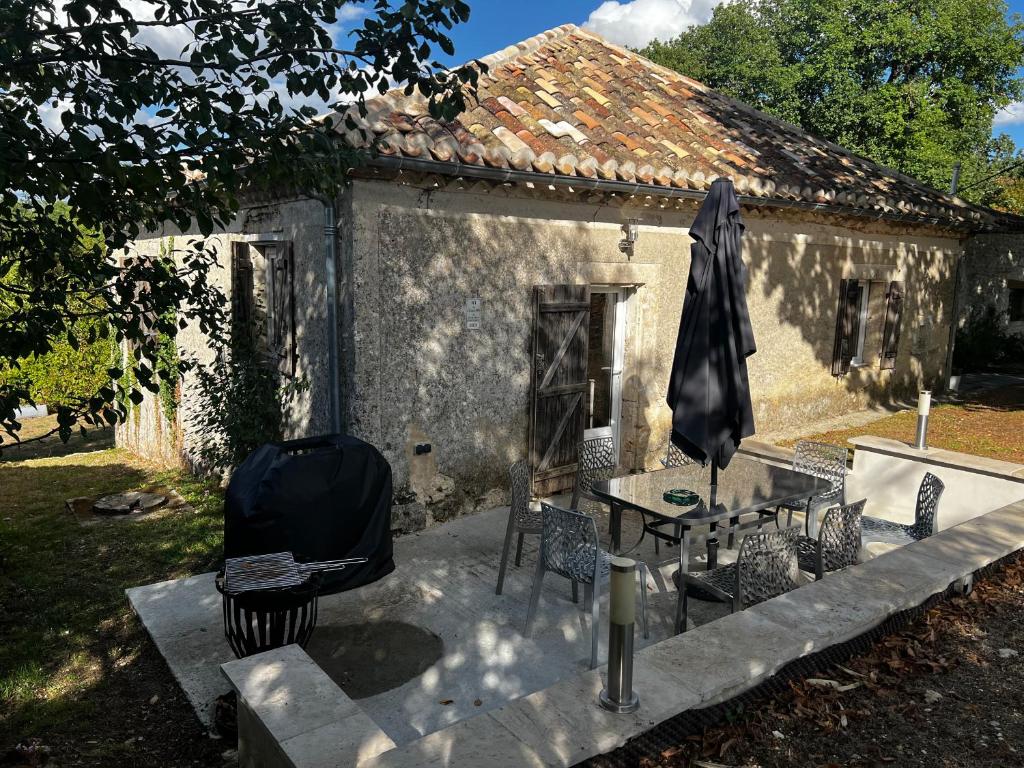 a patio with chairs and a table and an umbrella at Gîte loustalneve in Bourg-de-Visa