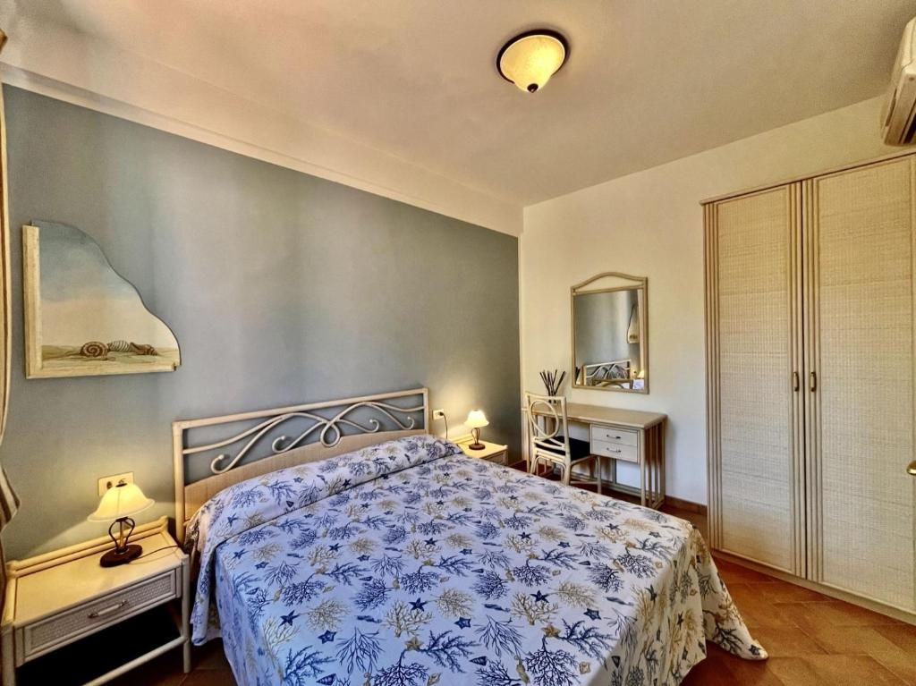 a bedroom with a bed with a blue and white bedspread at Sera & Mattino Appartamenti by SolturElba in Capoliveri