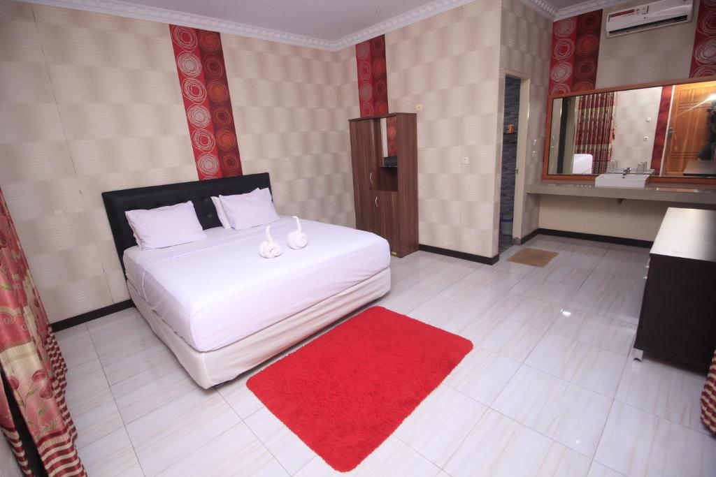 a bedroom with a white bed and a red rug at Tangkoko Lodge in Bitung