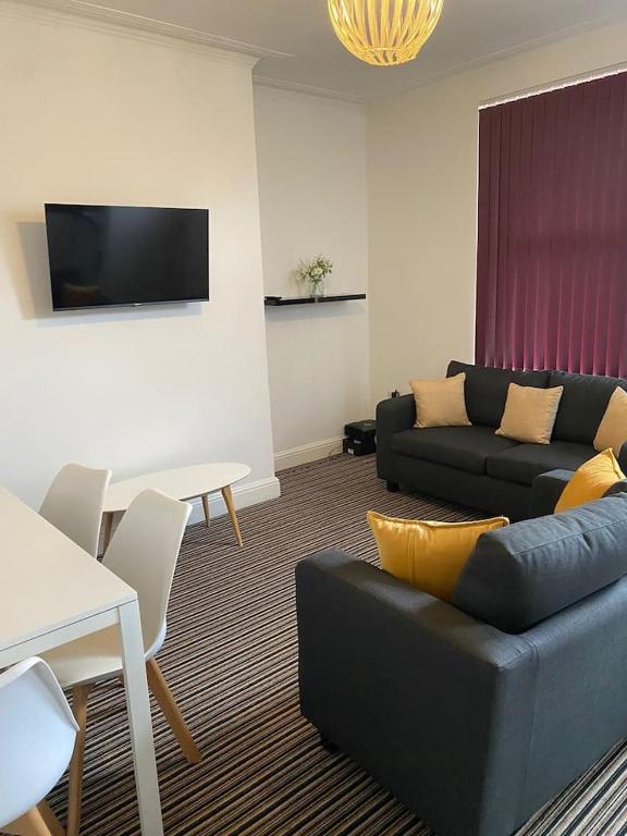 a living room with a couch and a table at Spacious house with 3 ensuite bedrooms in Leeds in Leeds