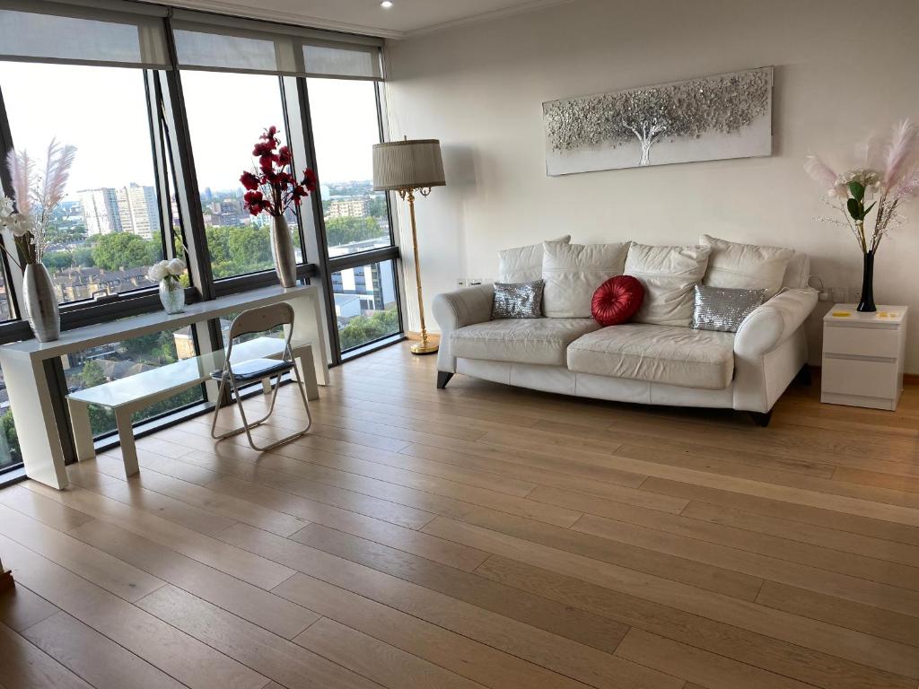 a living room with a white couch and floor to ceiling windows at 1 Bed- Dedicated Workspace, Coffee maker 4KTV in London