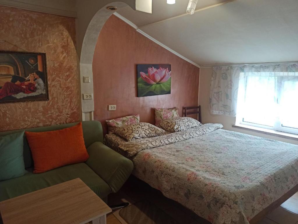 een slaapkamer met een bed, een bank en een raam bij Готель Жасмин in Ternopilʼ