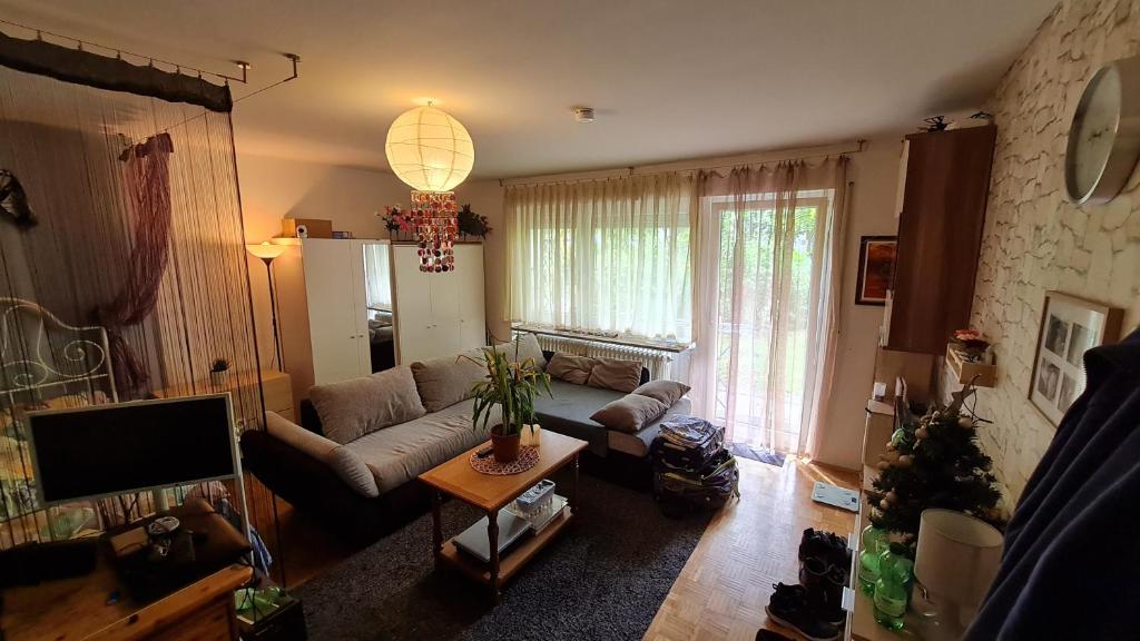 uma sala de estar com um sofá e uma televisão em Akropolitan Schönes Zimmer in einer Wohnung mit eigenem großen Garten em Munique
