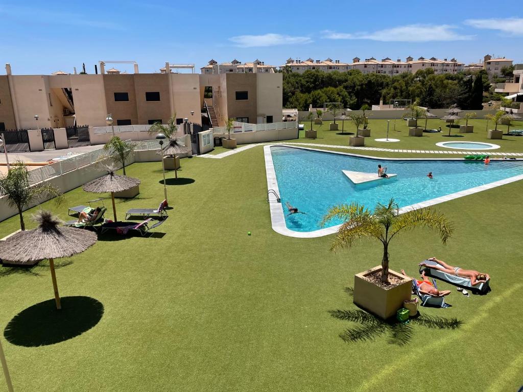 an overhead view of a swimming pool with grass and umbrellas at Residencial Sabrina in Playas de Orihuela