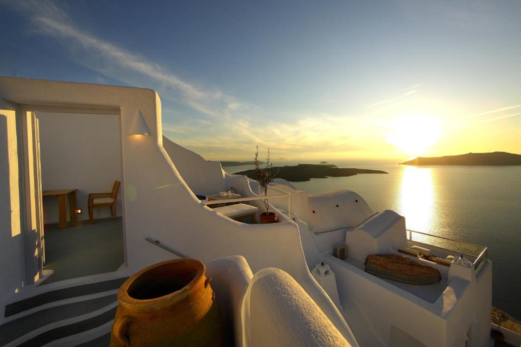 un coucher de soleil sur le côté d'un bateau dans l'eau dans l'établissement Ikastikies Suites, à Firostefani