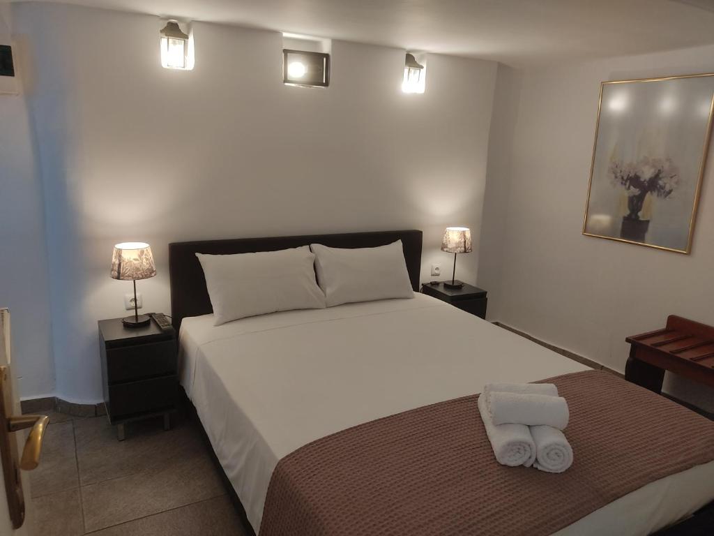 a bedroom with a large white bed and two lamps at Xenonas ΚITHΑIRON in Vília