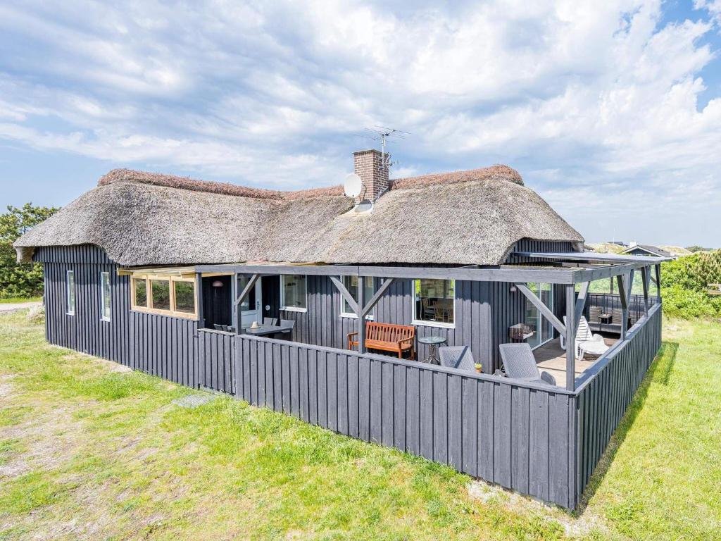 a large black house with a thatched roof at Holiday home Hvide Sande LXIX in Havrvig
