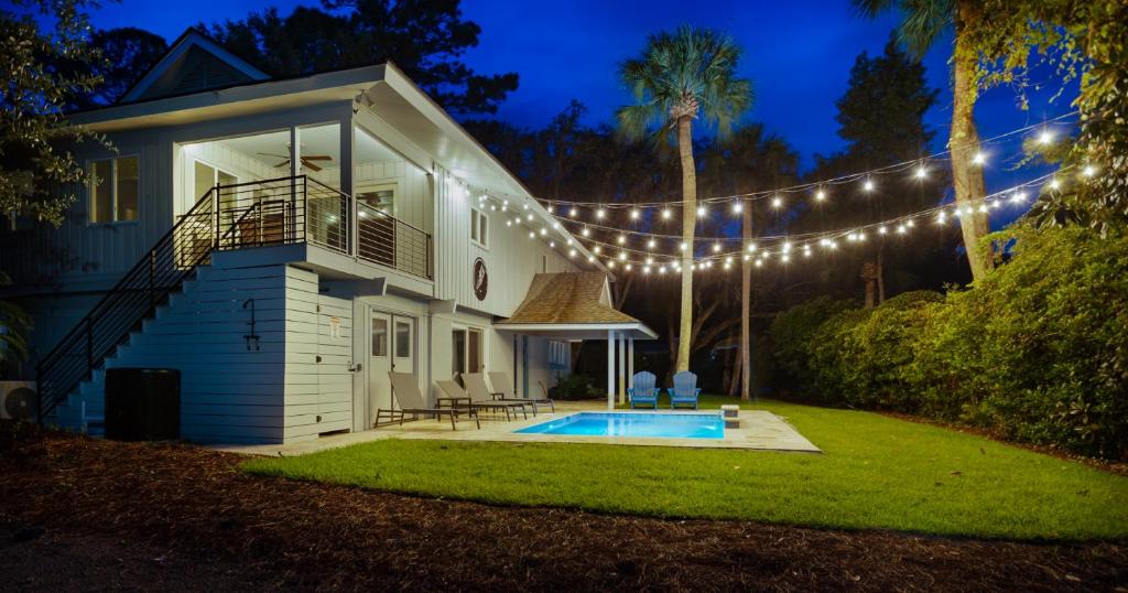 a house with a string of lights around a swimming pool at Luxury Beach House - 2min Walk to Beach - Private Pool - Group & Dog Friendly in Hilton Head Island