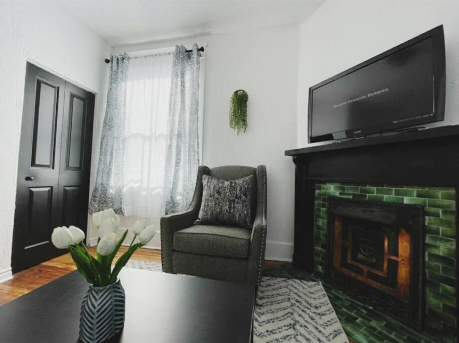 a living room with a fireplace with a television and a chair at Lovely 2BR w Office space - KING BED & ALEXA in Pittsburgh