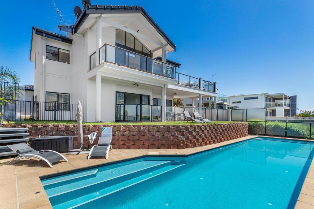 a house with a swimming pool in front of a house at Above and Beyond - Beautiful Home with Heated Pool and Views in Salamander Bay