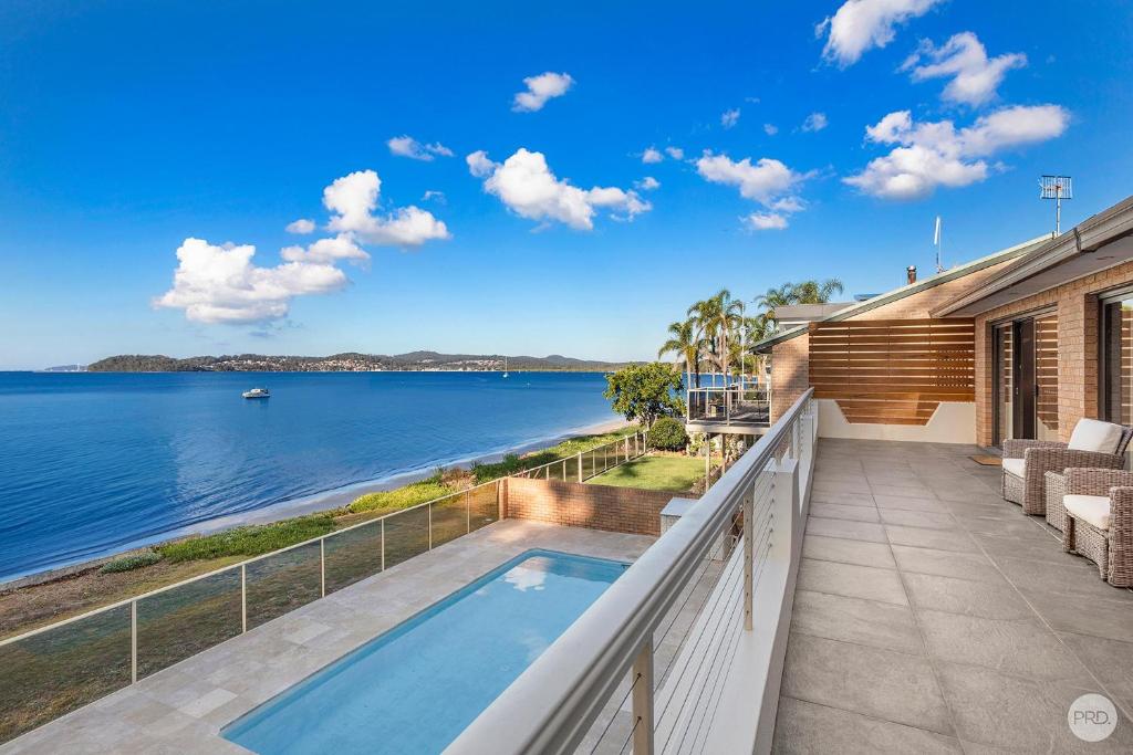 a balcony with a view of the water at Seaside Sanctuary - Waterfront Luxury Home with Heated Pool in Salamander Bay