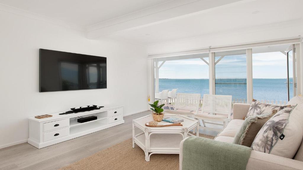 ein Wohnzimmer mit einem Sofa und einem TV in der Unterkunft The Beach Shack on Wanda - Brand New Beachfront Luxury in Salamander Bay