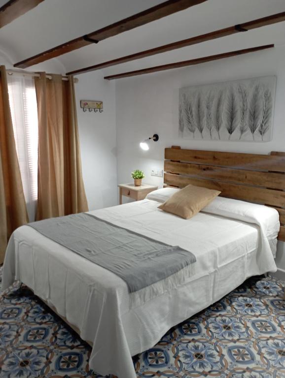 a bedroom with a large bed with a wooden headboard at El MANANTIAL in Zahara de la Sierra