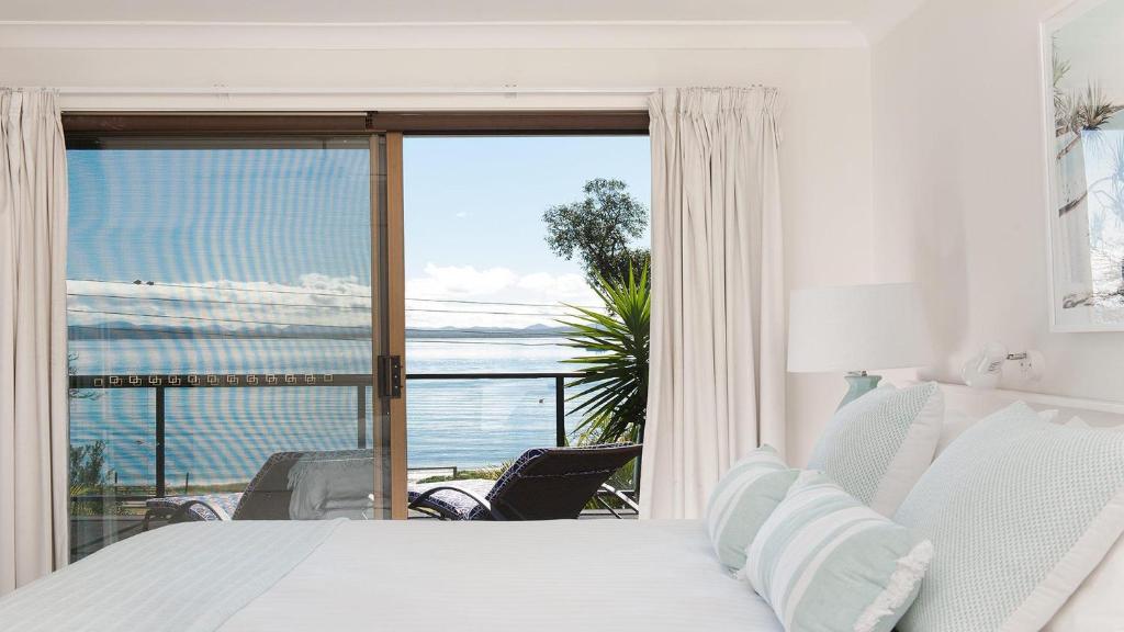 a bedroom with a bed and a view of the ocean at Dutchie's Dream - Glorious Views And Opposite Dutchies Beach in Nelson Bay