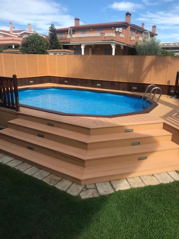a swimming pool with a wooden deck around it at VILLA NEVADA Esclusiva con PISCINA Privata, Il Tuo Angolo di Pace a 5 Minuti dal MARE e 20 Minuti da ROMA in Ladispoli