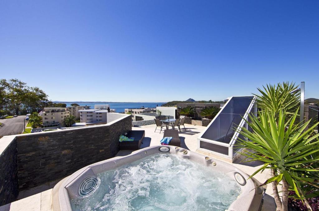 a hot tub on a patio with the ocean in the background at Harbour View Penthouse - The Perfect Location in Nelson Bay