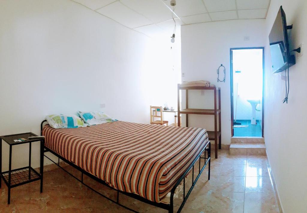 ein Schlafzimmer mit einem Bett mit einer gestreiften Decke in der Unterkunft Hostal Los Faroles Chicoana in Chicoana