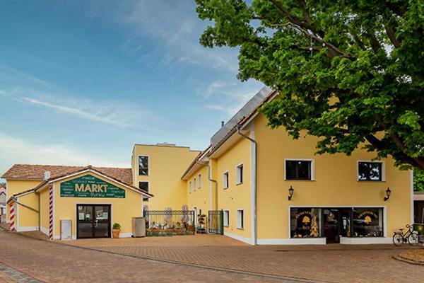 ein großes gelbes Gebäude mit einem Laden auf einer Straße in der Unterkunft Eichengrund Cochstedt in Hecklingen