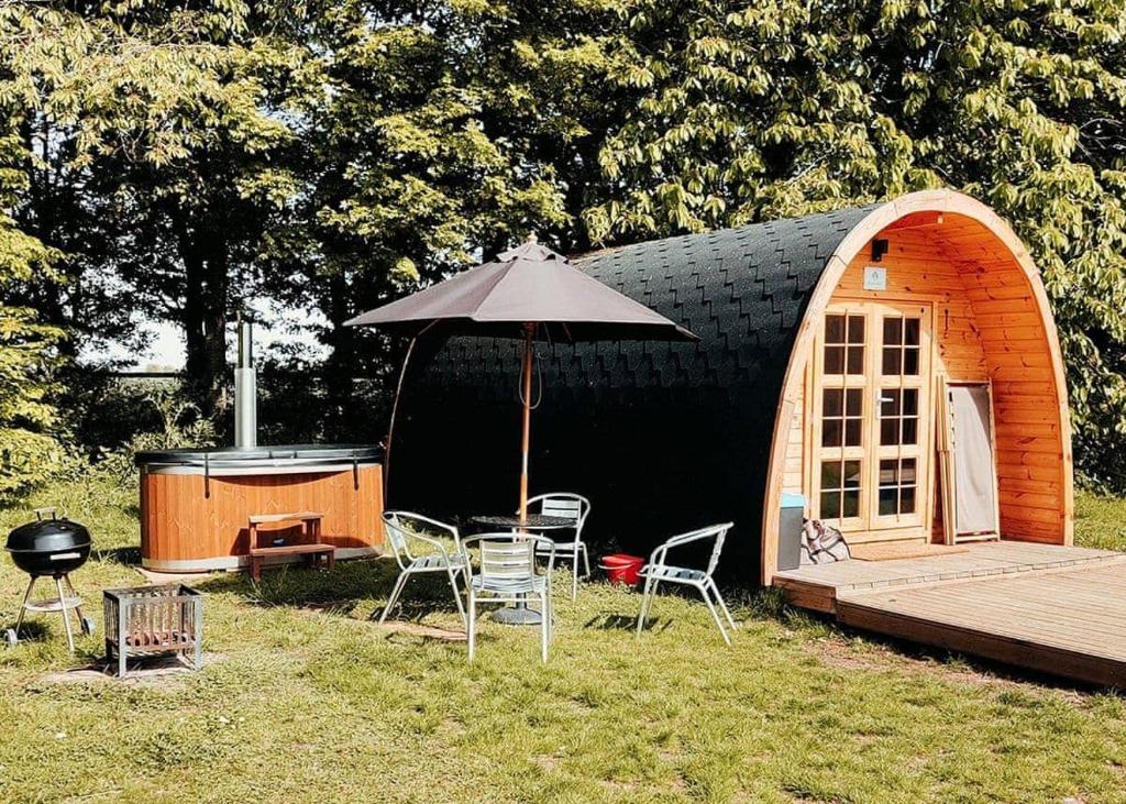 een kleine hut met een tafel en stoelen en een parasol bij Apple Mount Retreat in Lavenham