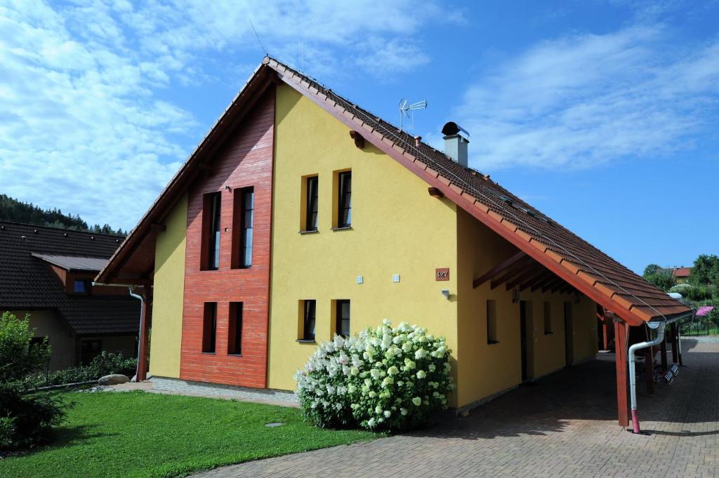 a yellow house with a red roof with a flower at Hortenzie in Kašperské Hory