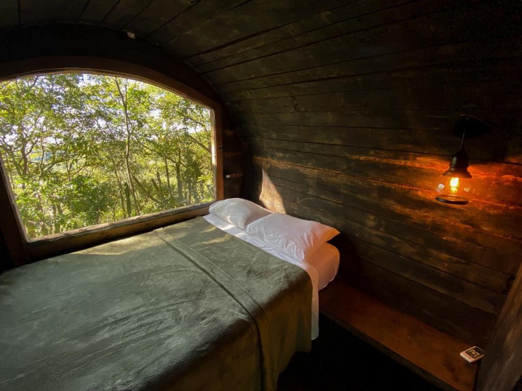 1 dormitorio con ventana en una cabaña de madera en Salto Suizo Parque Ecologico, en Independencia