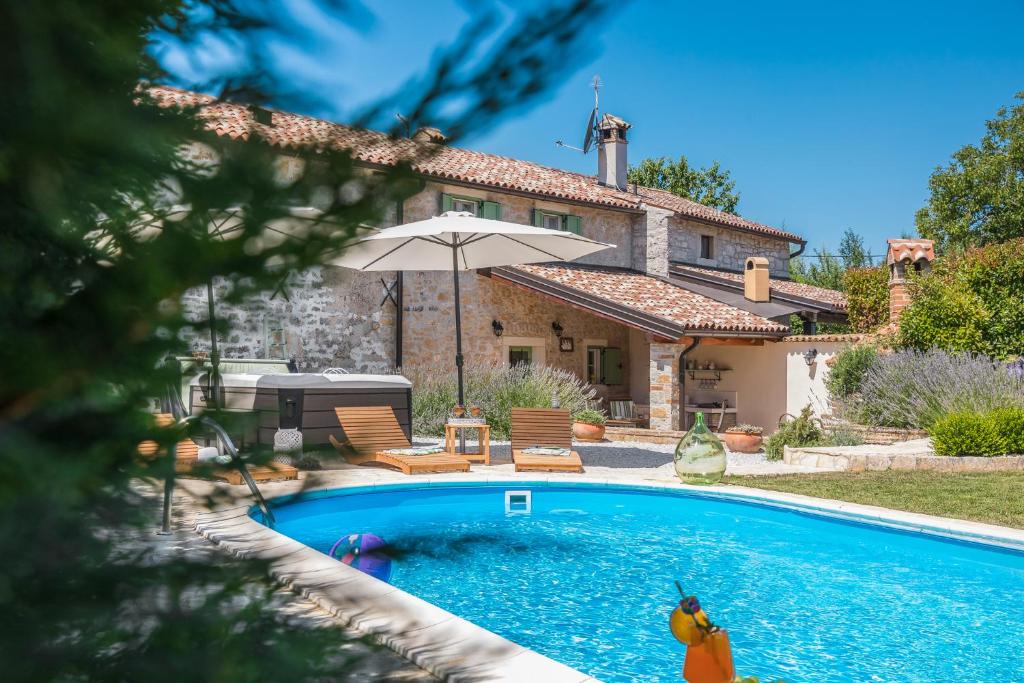 a house with a swimming pool in front of a house at Villa Nonni-romantic stone house in Višnjan