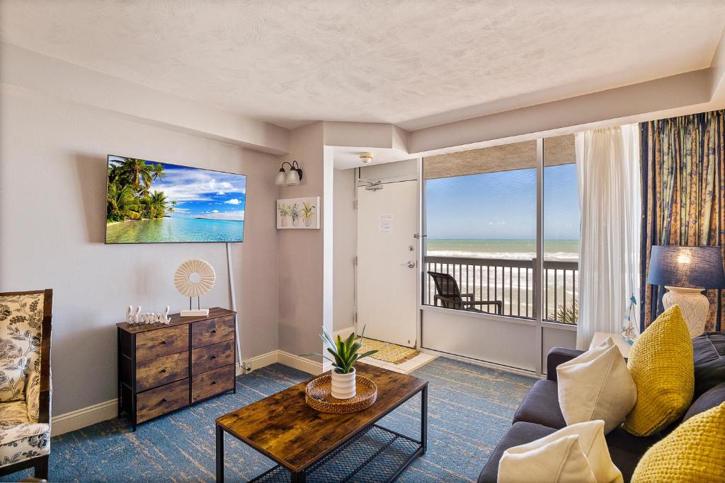 Sunrise & Beach View - Daytona Beach Resort في دايتونا بيتش: غرفة معيشة مع أريكة وطاولة