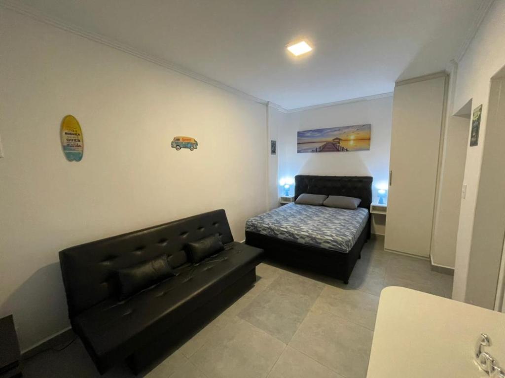 uma sala de estar com um sofá e uma cama em Kitnet Premium Canto do Forte - Praia Grande na Praia Grande