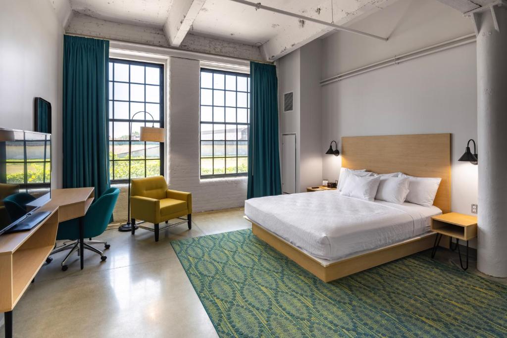 una camera d'albergo con letto, scrivania e sedie di The Warehouse Hotel at Champion Mill a Hamilton