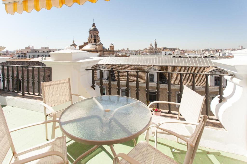 una mesa de cristal y sillas en un balcón con vistas en Apartamentos Diaber Laraña, en Sevilla