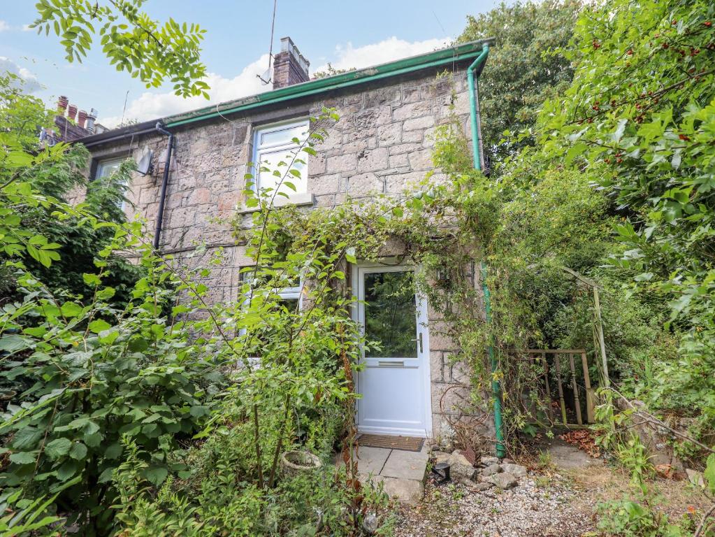 an old stone cottage with a white door at 26 Llawr Pentre in Colwyn Bay