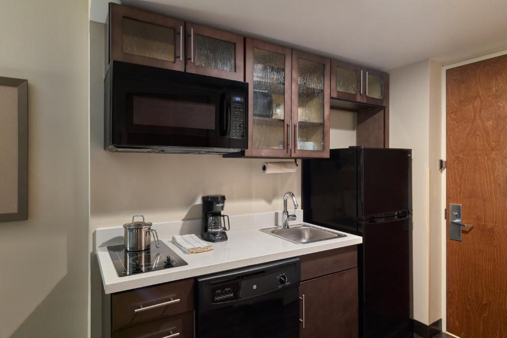 a kitchen with a sink and a black refrigerator at Candlewood Suites NYC -Times Square, an IHG Hotel in New York