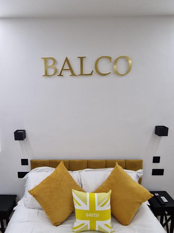 a bed with yellow pillows and a sign on the wall at Balco Vista Studio in Nottingham