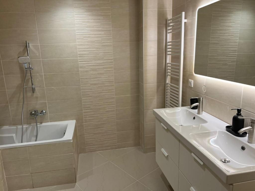 La salle de bains est pourvue d'un lavabo, d'une baignoire et d'un miroir. dans l'établissement App 2 Mulhouse centre , 6 personnes, à Mulhouse