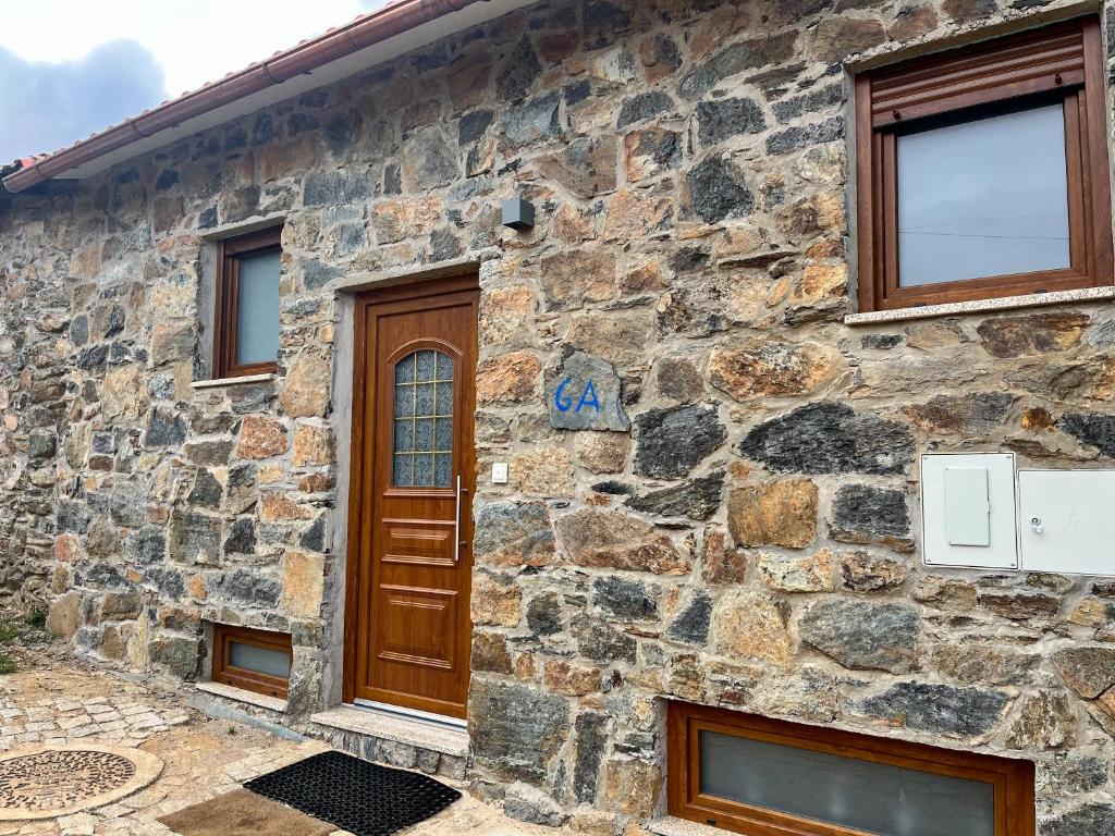 Casa da Barriada II في براغانزا: منزل حجري بباب خشبي ونوافذ