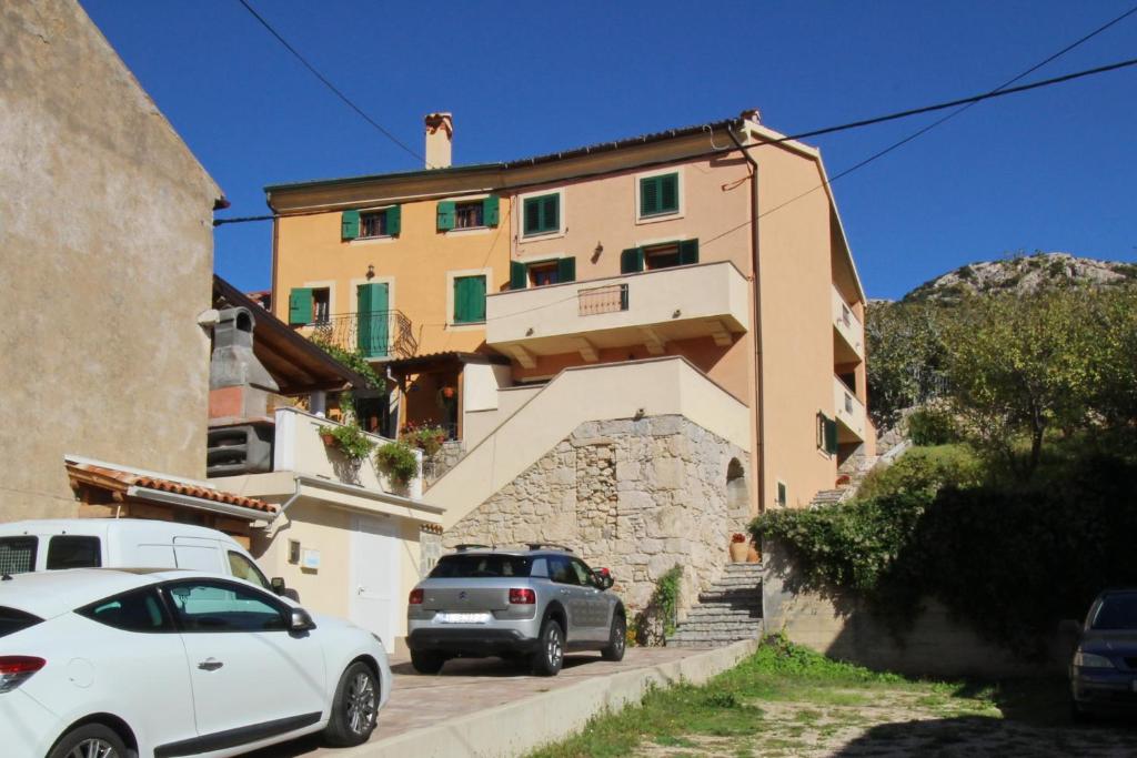 a building with two cars parked in front of it at Holiday house with a swimming pool Draga Bascanska, Krk - 19204 in Draga Bašćanska