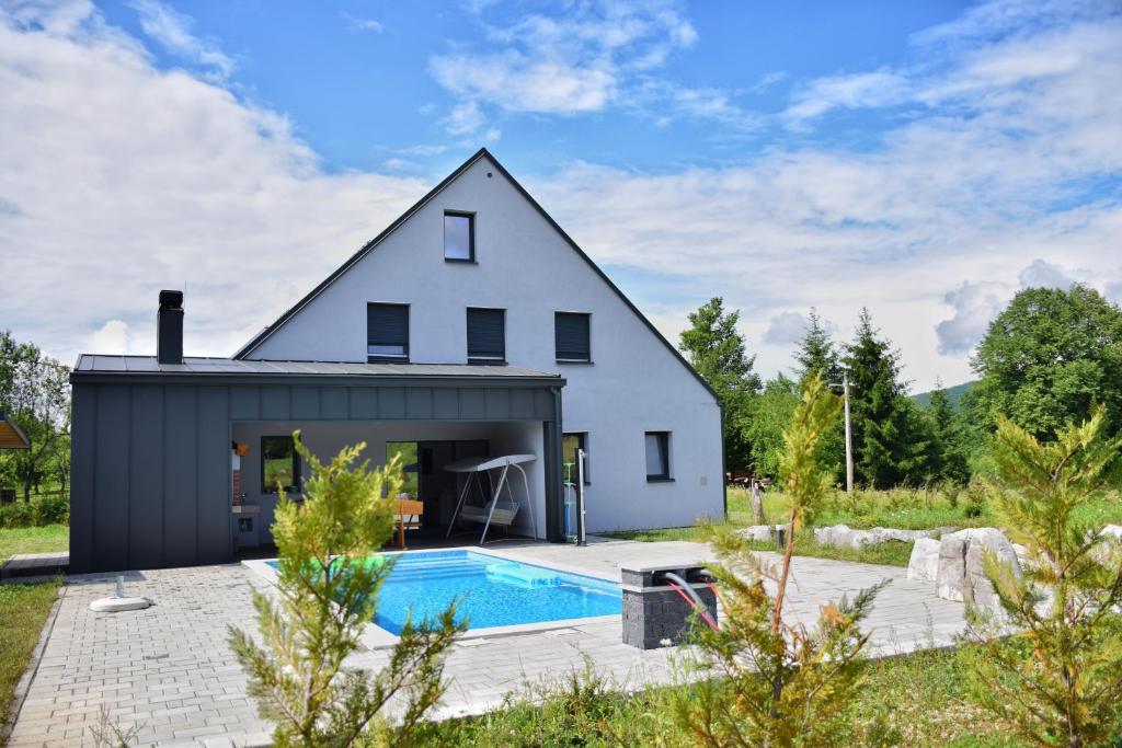 a white house with a swimming pool in front of it at Family friendly house with a swimming pool Ostarije, Gorski kotar - 18952 in Ogulin