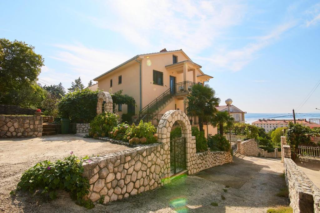 a house with a stone fence and a stone wall at Apartments and rooms with parking space Crikvenica - 19125 in Crikvenica