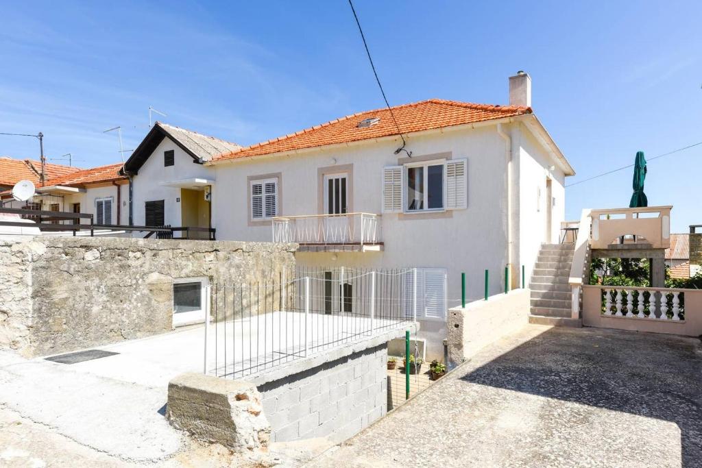 uma casa branca com uma cerca à frente. em Apartments by the sea Kali, Ugljan - 19137 em Kali