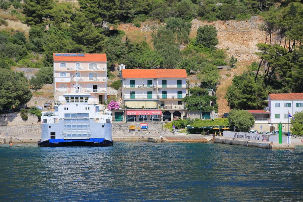 ein im Wasser neben einem Gebäude angedocktes Boot in der Unterkunft Apartments by the sea Drvenik Donja vala, Makarska - 19006 in Drvenik