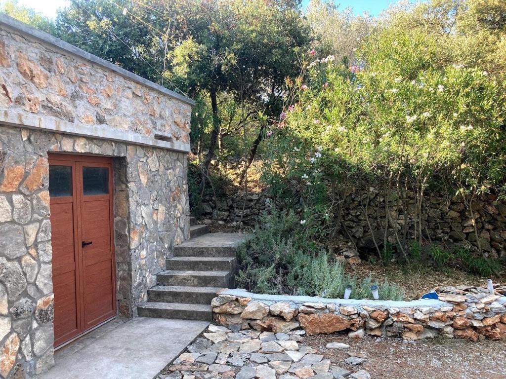 a stone building with a wooden door and stairs at Secluded fisherman's cottage Zman, Dugi otok - 19000 in Žman