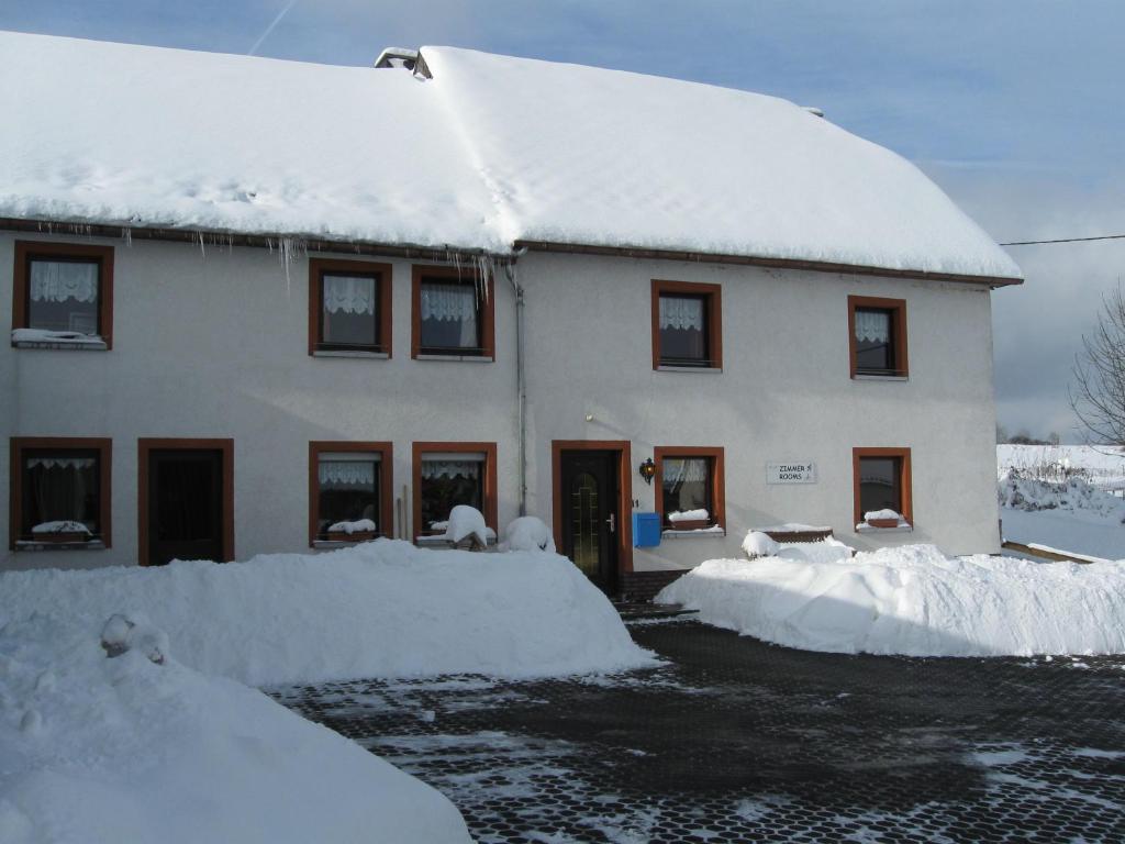 uma casa coberta de neve em frente dela em B&B Snow View Lodge em Medendorf